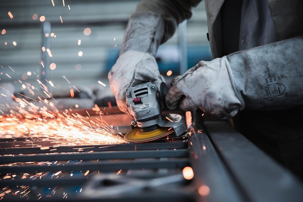 Artisan utilisant une meuleuse avec étincelles sur du métal