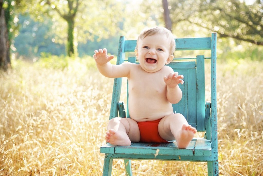 Bébé souriant assis sur une petite chaise en extérieur