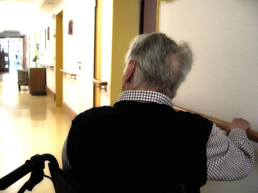 Homme âgé marchant dans un couloir de résidence avec rampe