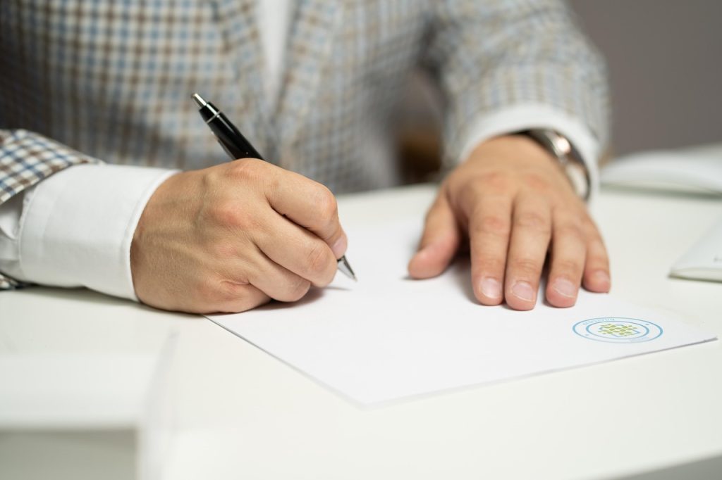 Une personne signe des documents administratifs