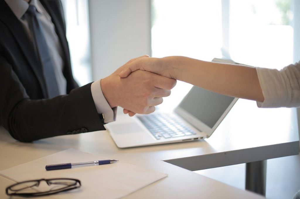 Poignée de main professionnelle au-dessus d'un bureau avec ordinateur