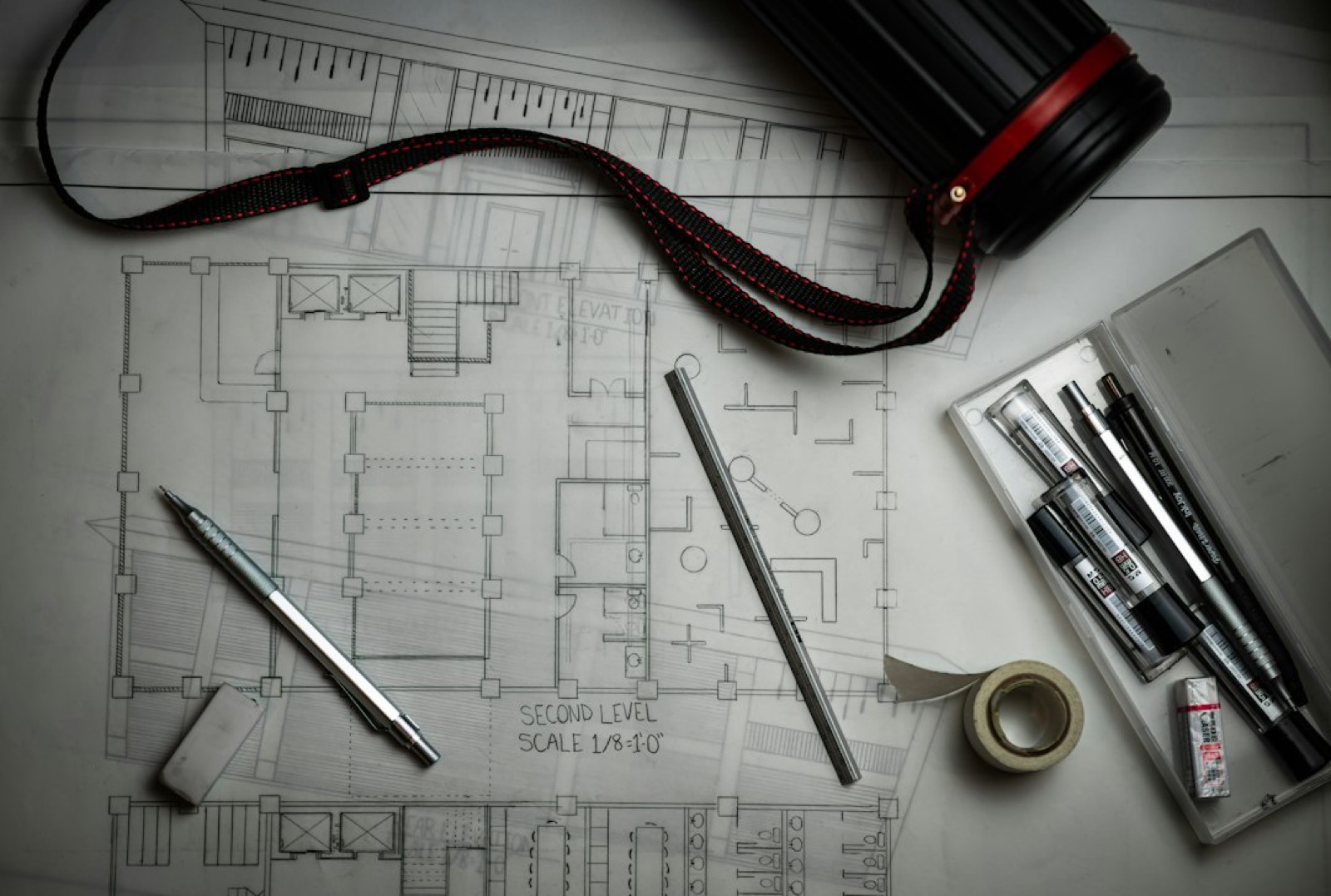 Plan d'architecte d'un appartement posé sur un bureau, à côté d'un devis de géomètre