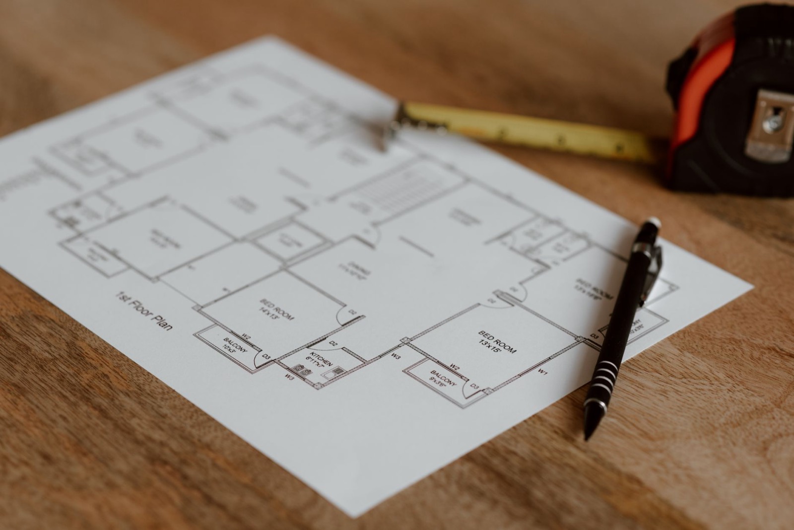Plan de relevé d'appartement posé sur une table avec des outils de géomètre