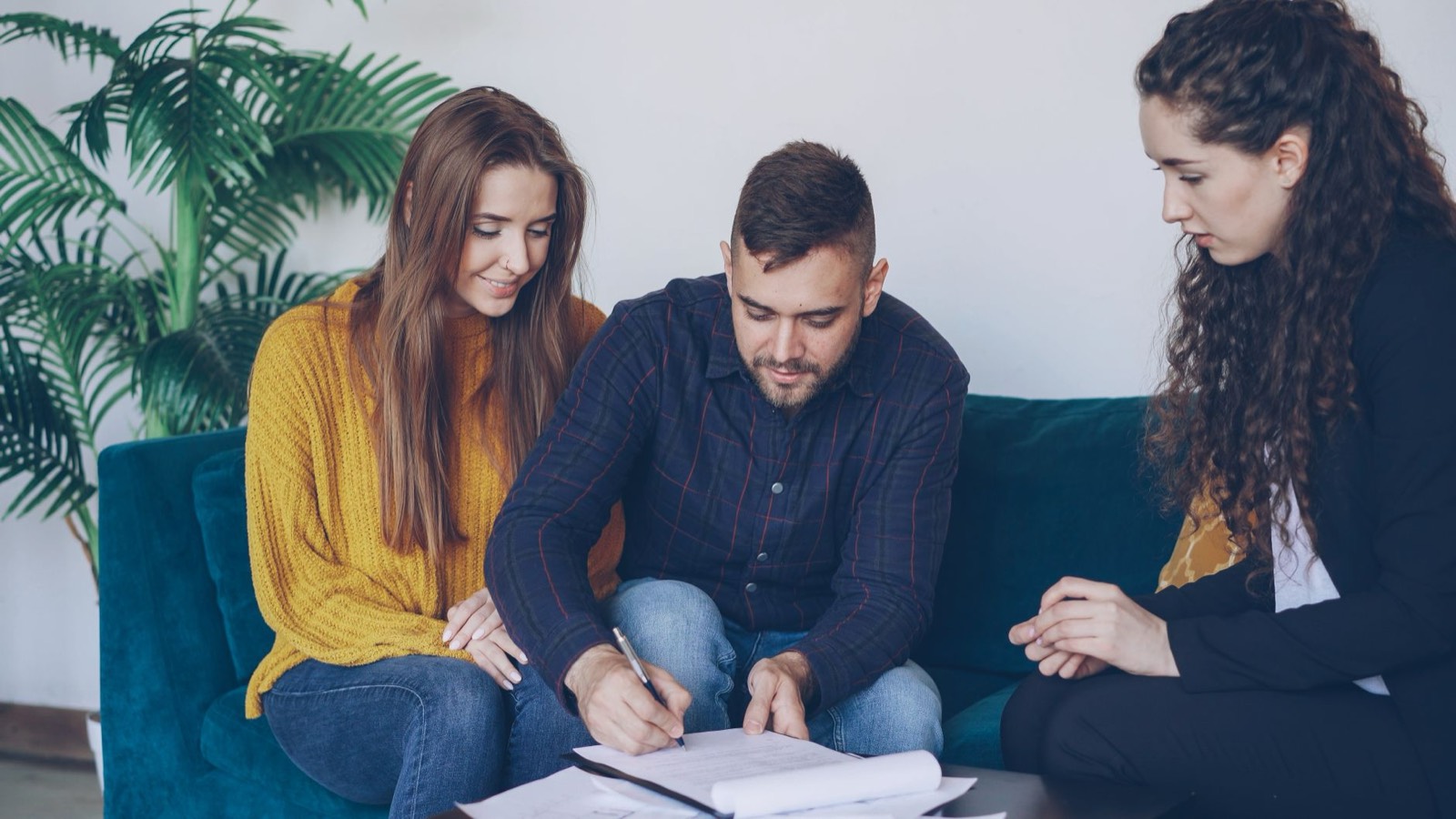 Un couple signe les documents d'un prêt immobilier sur une table de bureau